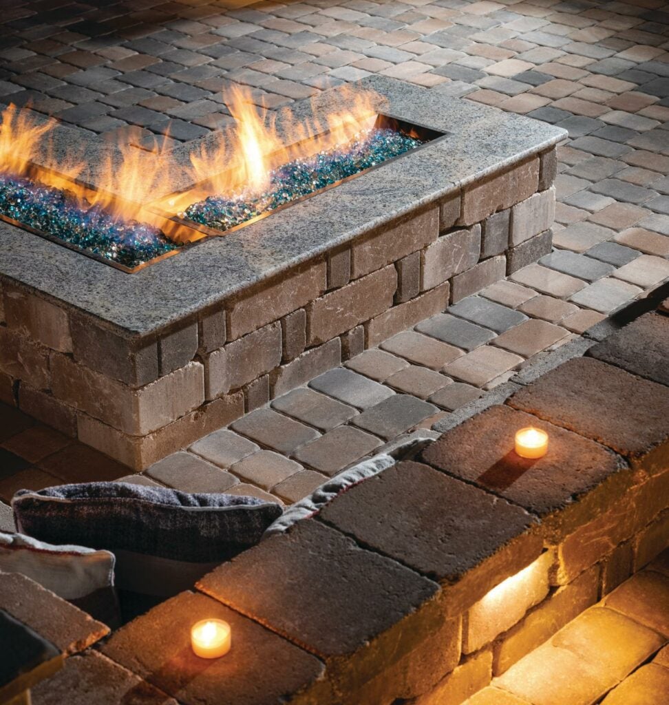 built-in L-shaped cobbled paver patio with custom fire table